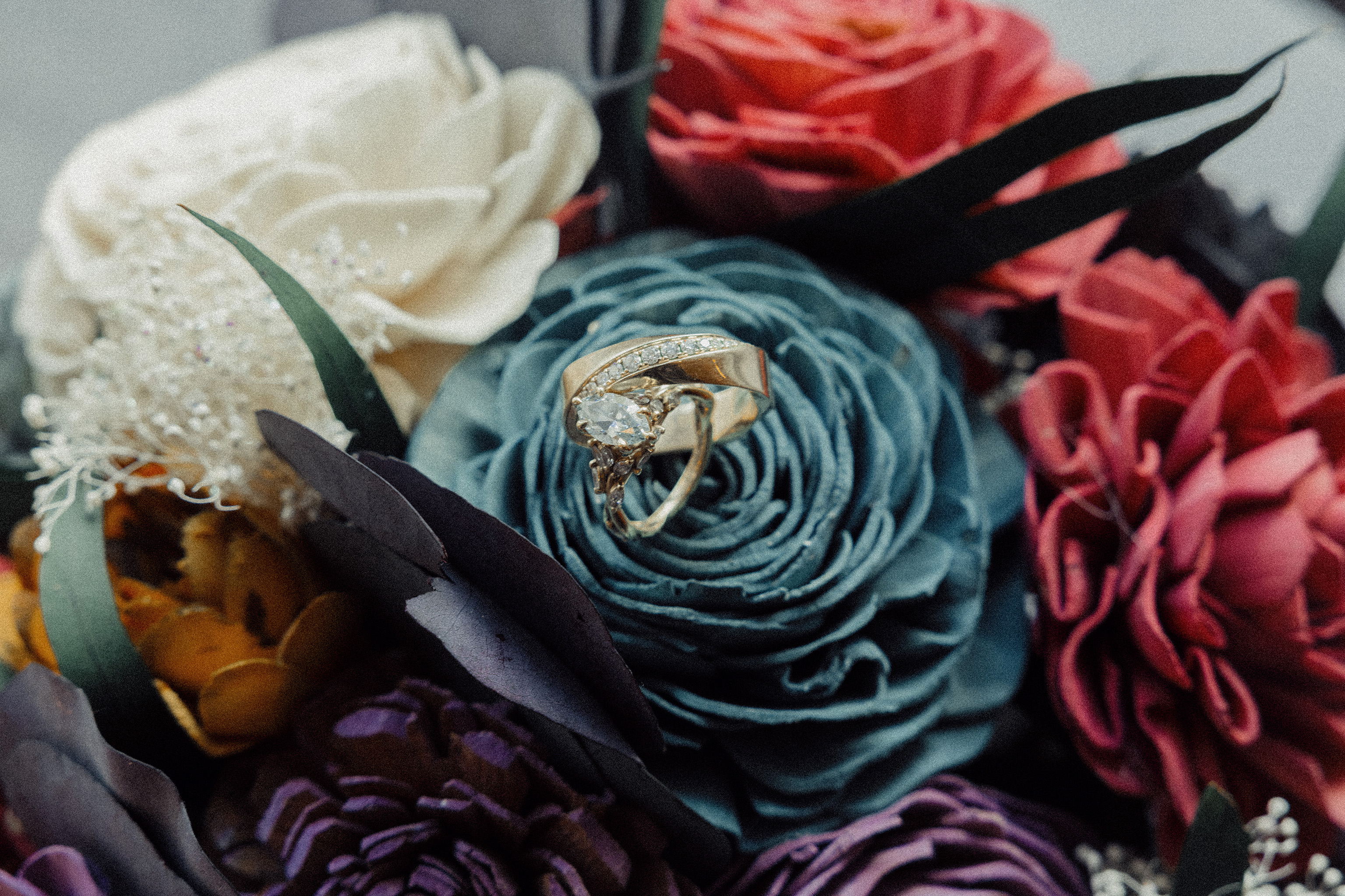 Close up of a moody floral wedding bouquet and gold rings